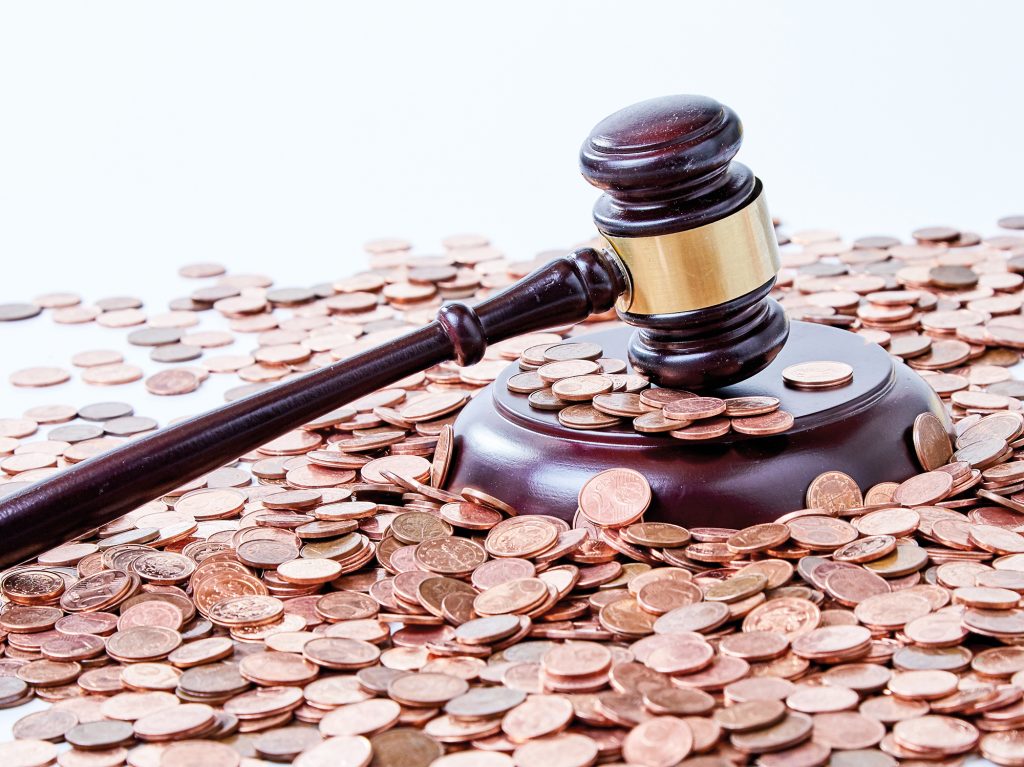 Immagine dei reati contro il patrimonio: il martelletto di un giudice su una distesa di monete