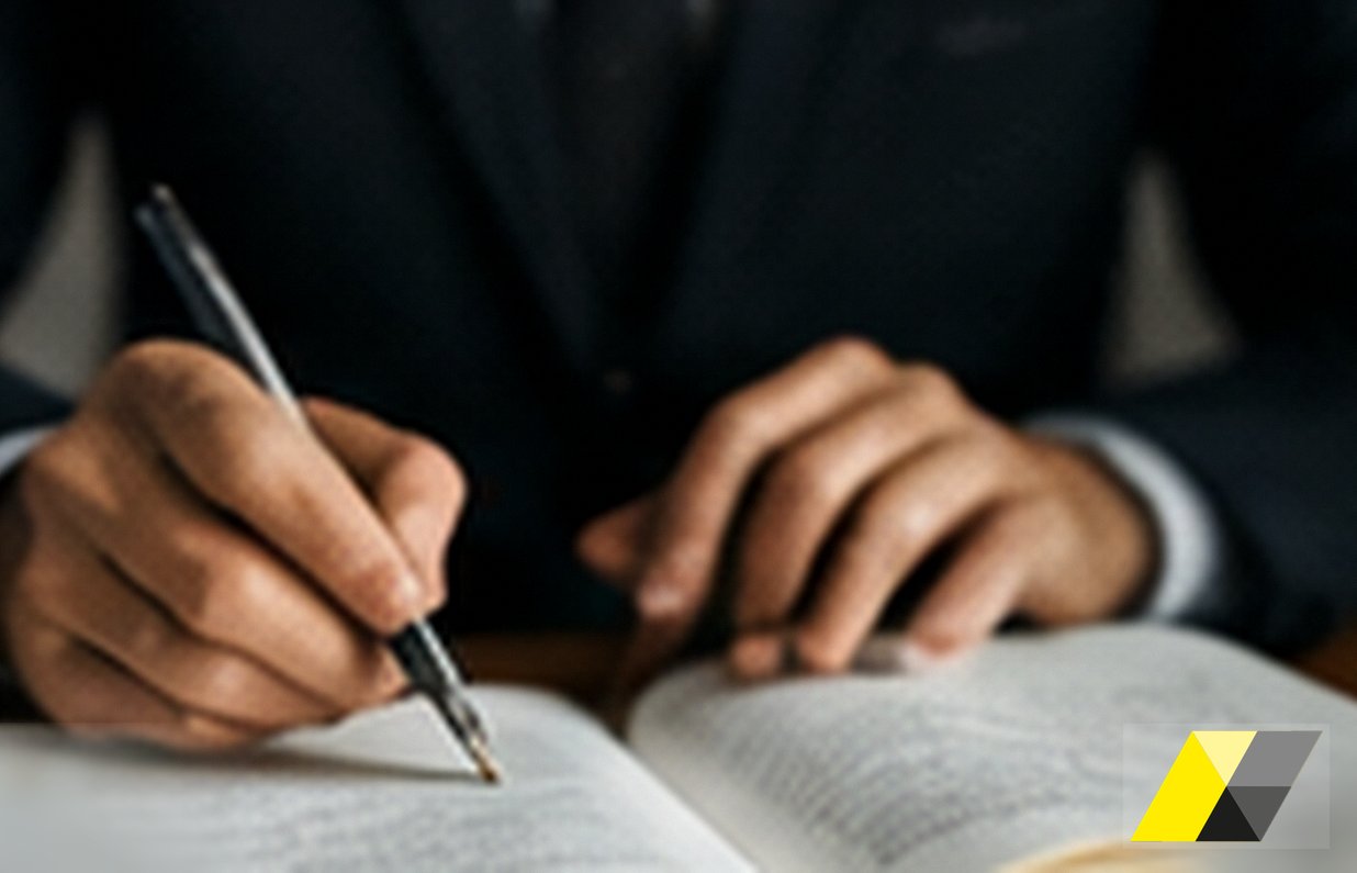 Mani che annotano con una penna su un libro aperto: gestore esterno whistleblowing, Soardi Studio Legale