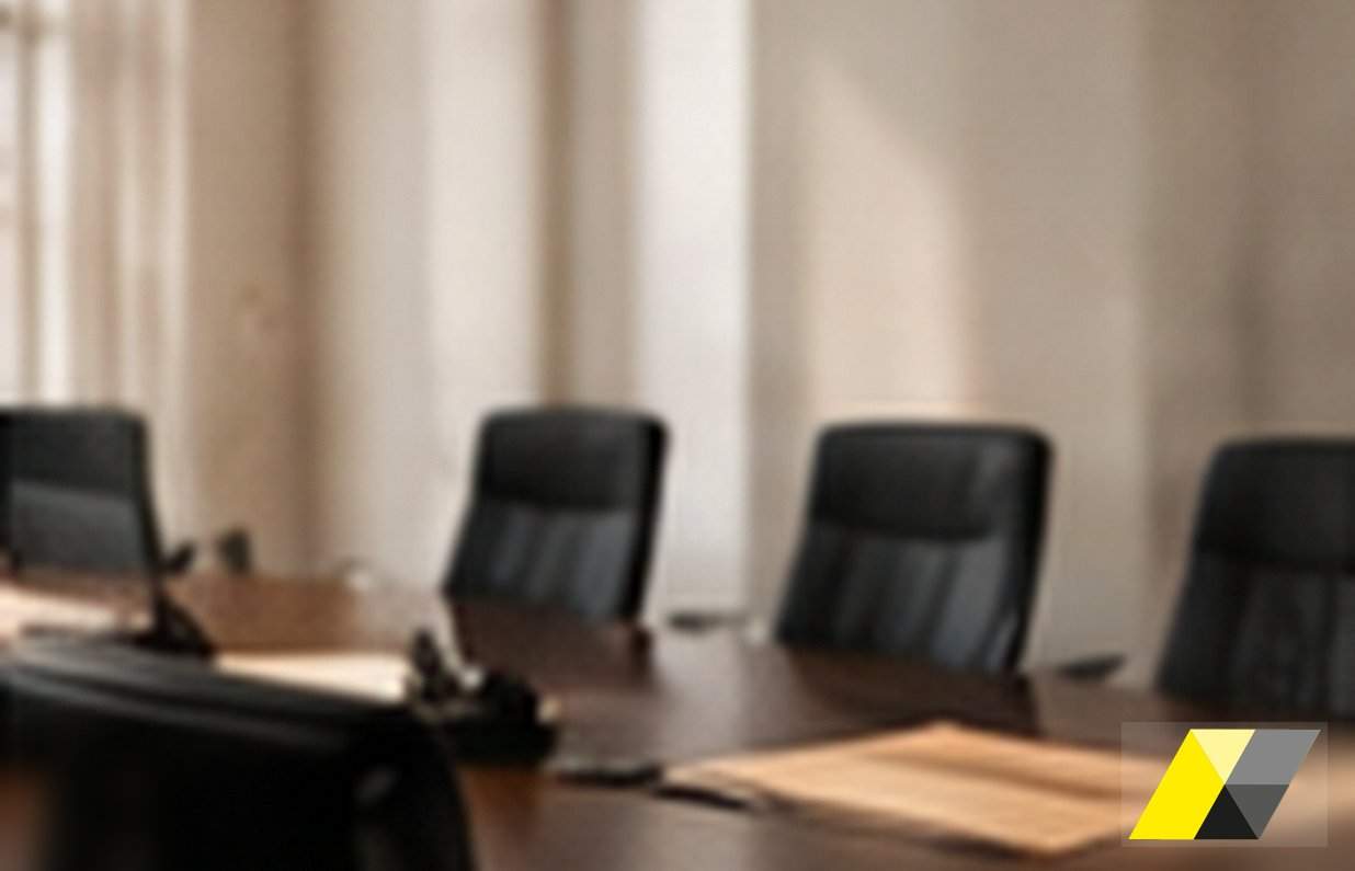 Sedie vuote attorno al tavolo di una sala riunioni con un fascicolo aperto: la procura speciale del difensore dell'ente si redige sugli atti, dopo il provvedimento da impugnare